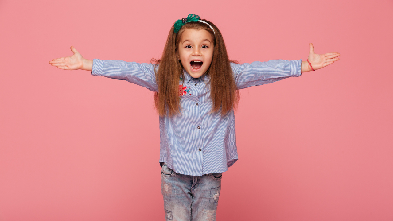 Счастливая маленькая девочка на розовом фоне