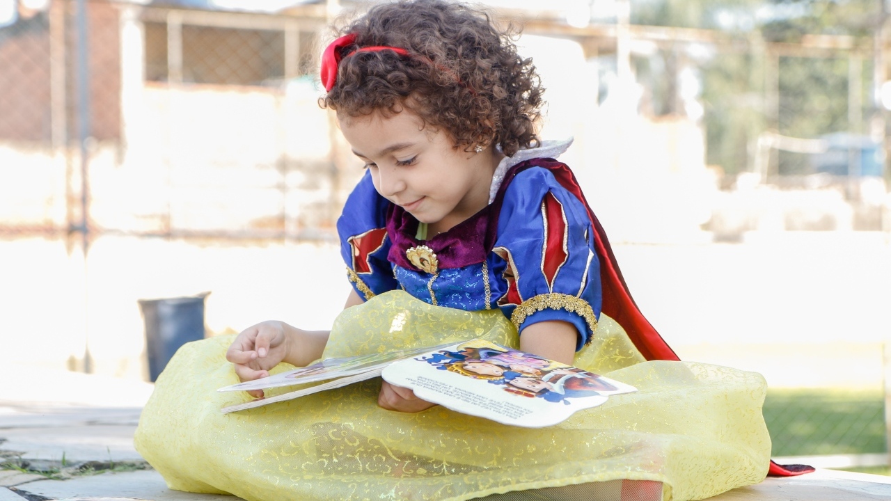 Маленькая девочка в костюме Белоснежки с книгой