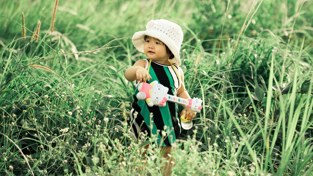 Маленькая девочка с игрушечной гитарой в траве