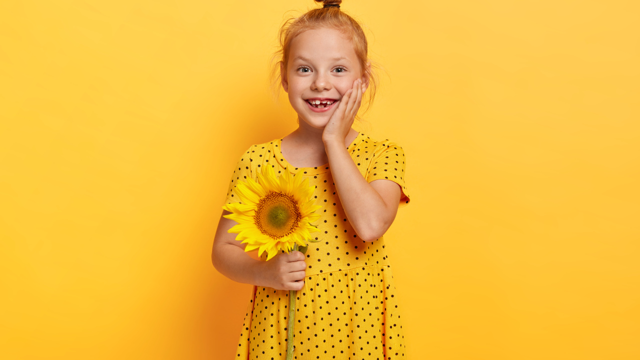 Маленькая рыжеволосая девочка с подсолнухом в руках