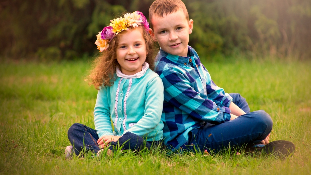 Рыжеволосые мальчик и девочка сидят на траве