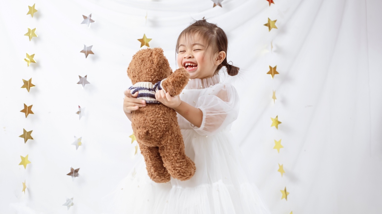 Улыбающаяся девочка азиатка с игрушечным медведем