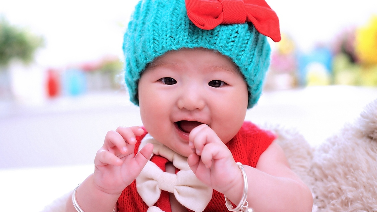 Улыбающаяся девочка в зеленой вязаной шапке