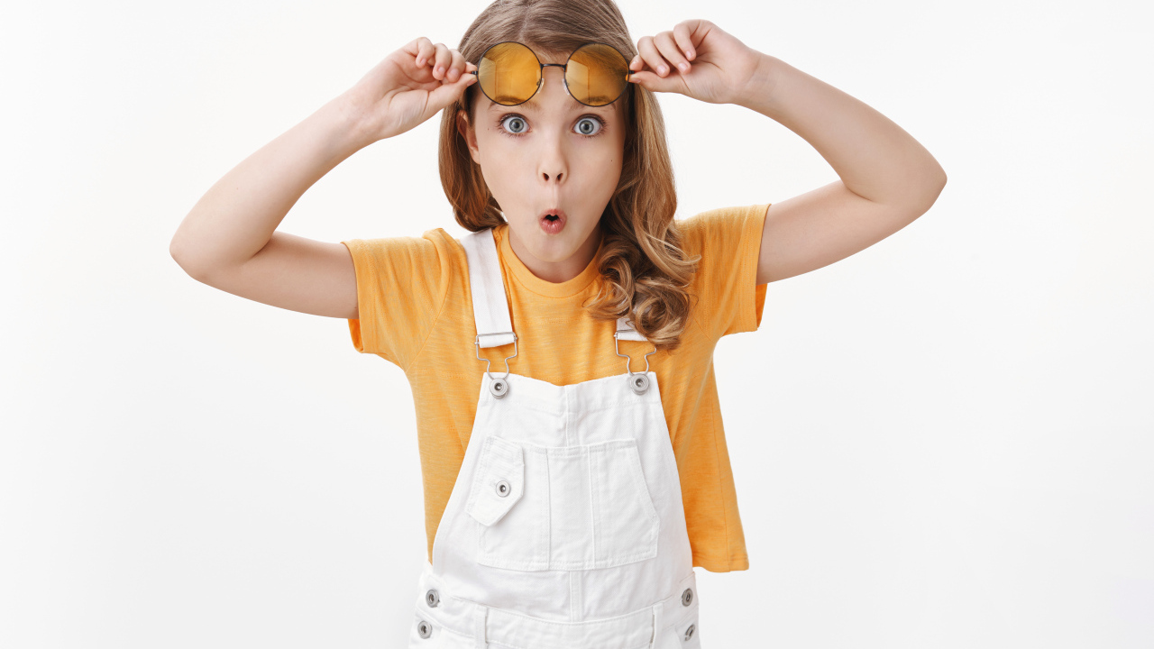 Удивленная девочка в очках на белом фоне