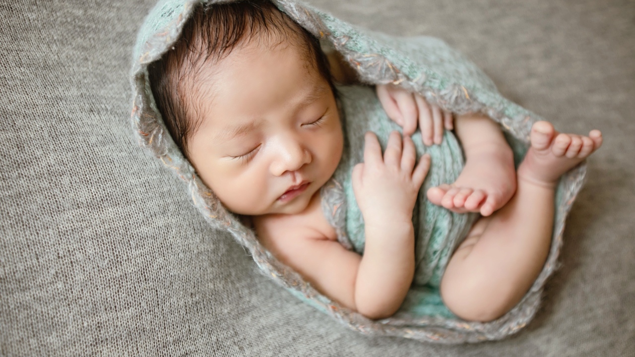 Крошечный новорожденный малыш на сером фоне