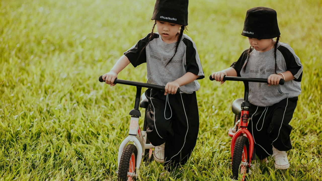 Две девочки с велосипедами на зеленой траве