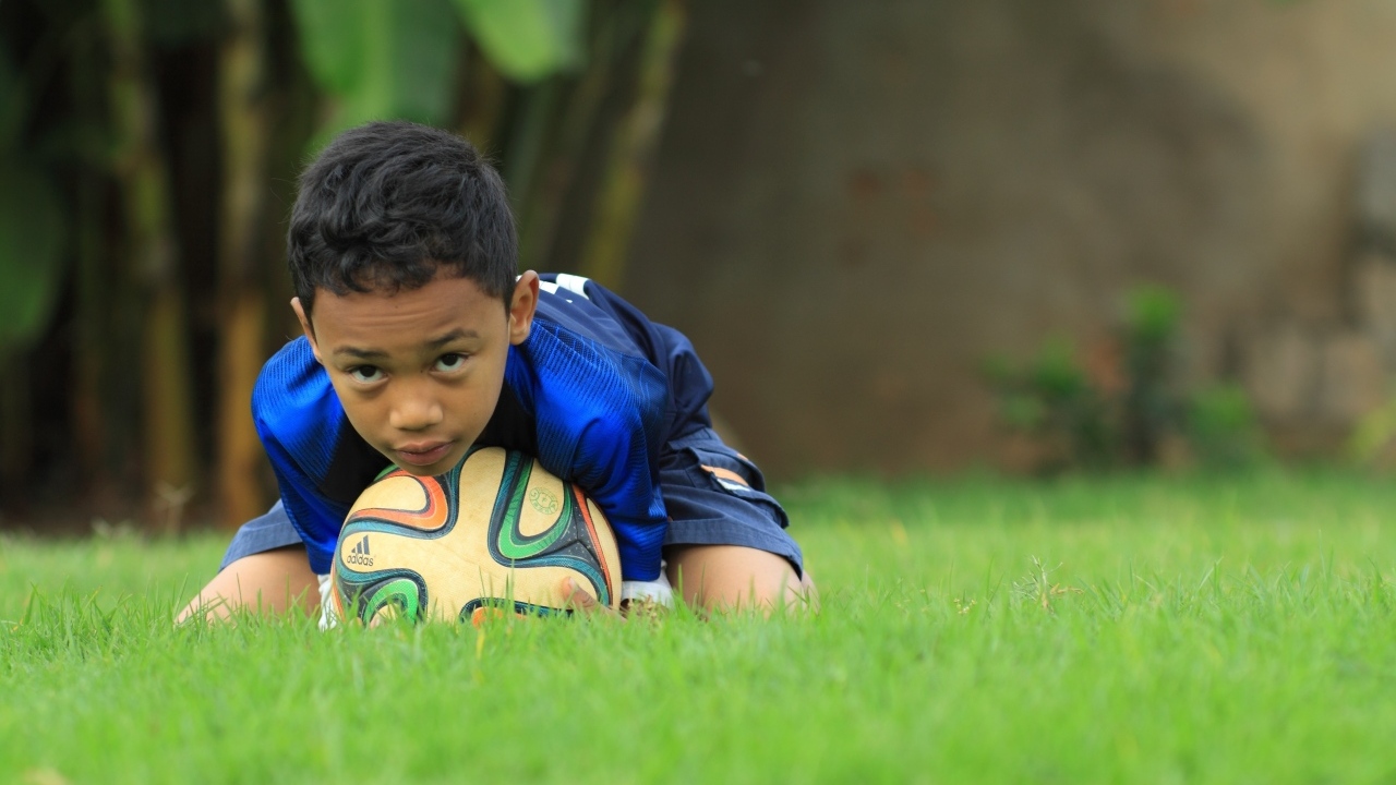 Мальчик юный футболист с мячом на поле