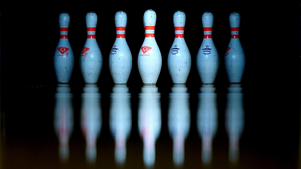 Кегли для боулинга отражаются в черной поверхности 