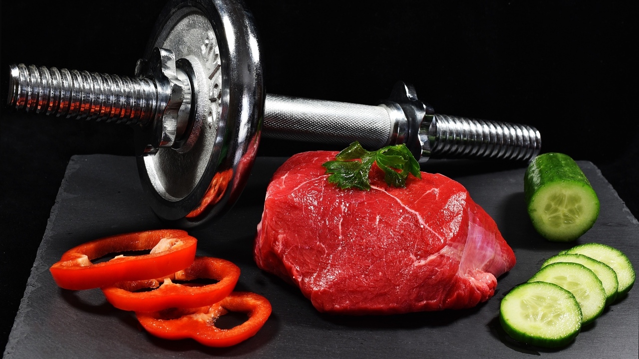 Гантеля и полезная еда для спортсмена на черном фоне