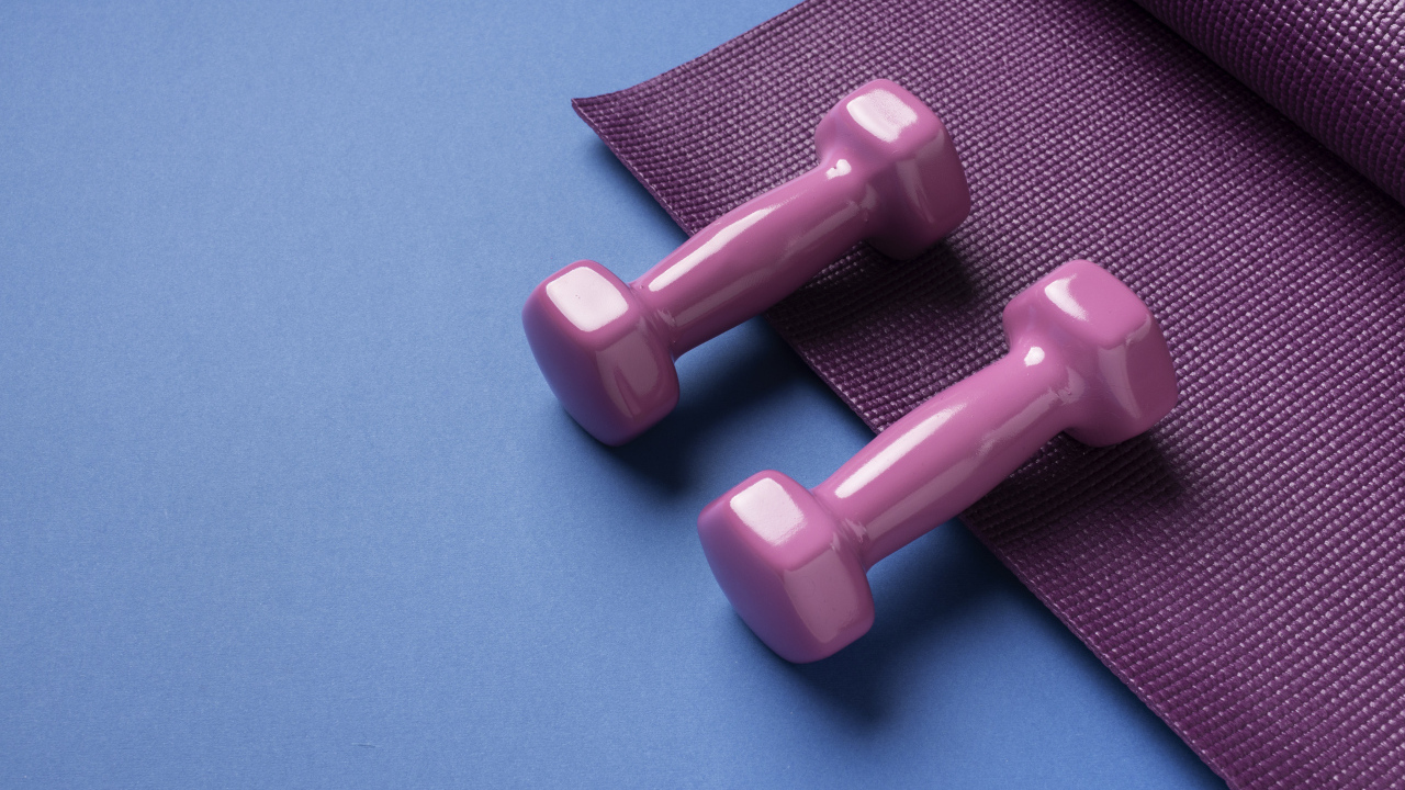 Розовые гантели и коврик на голубом фоне