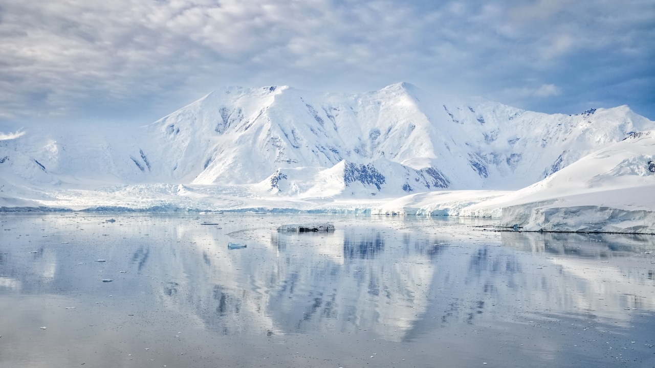 Заснеженные горы под белыми облаками у океана, Антарктида 