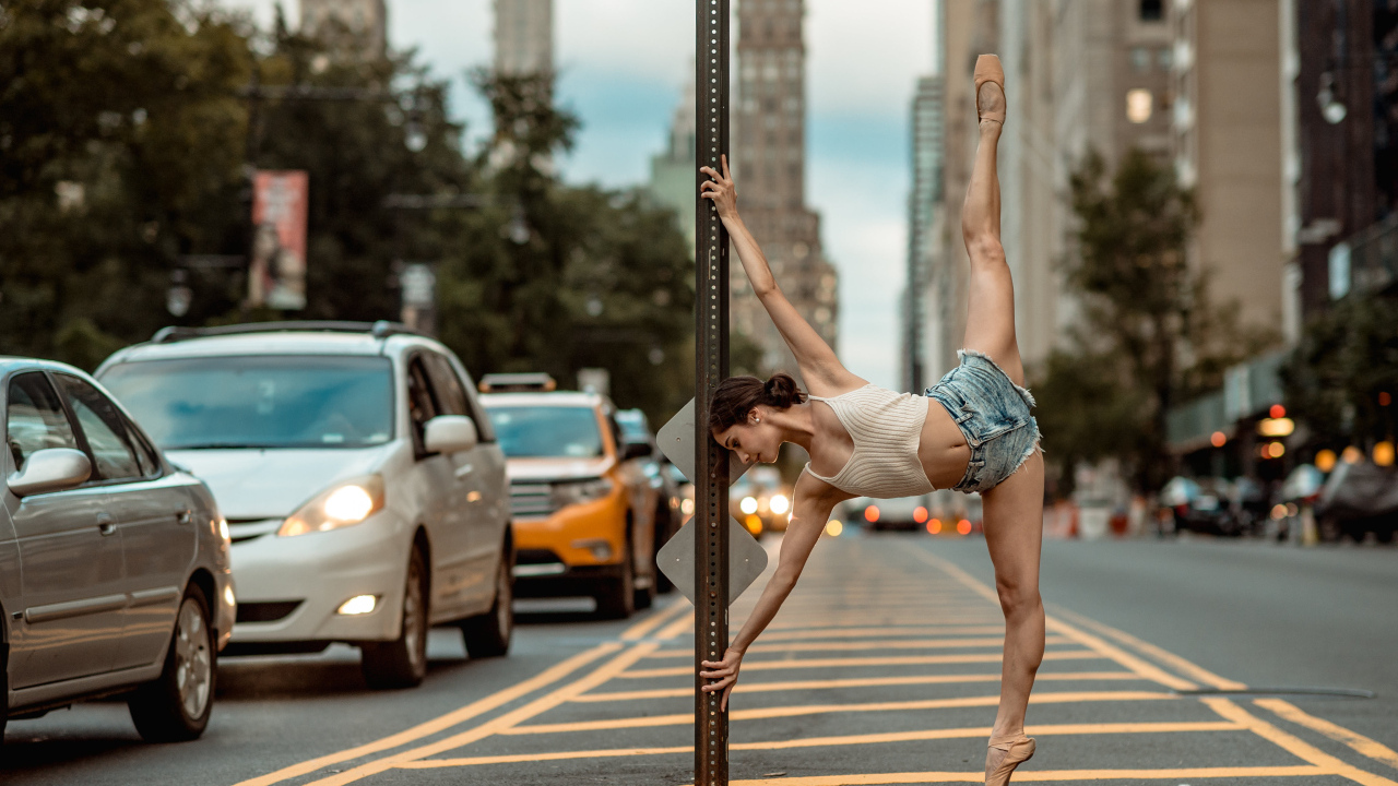 Девушка делает шпагат у столба в городе