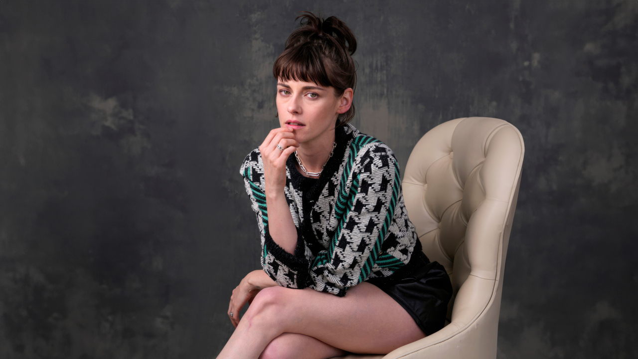 Актриса Кристен Стюарт сидит в кресле на фоне серой стены