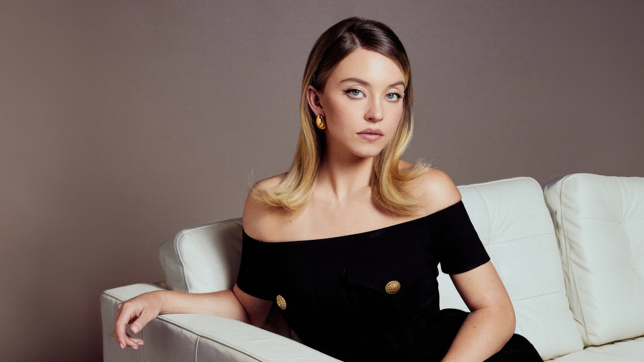 Актриса Сидни Суини в черном платье на белом диване