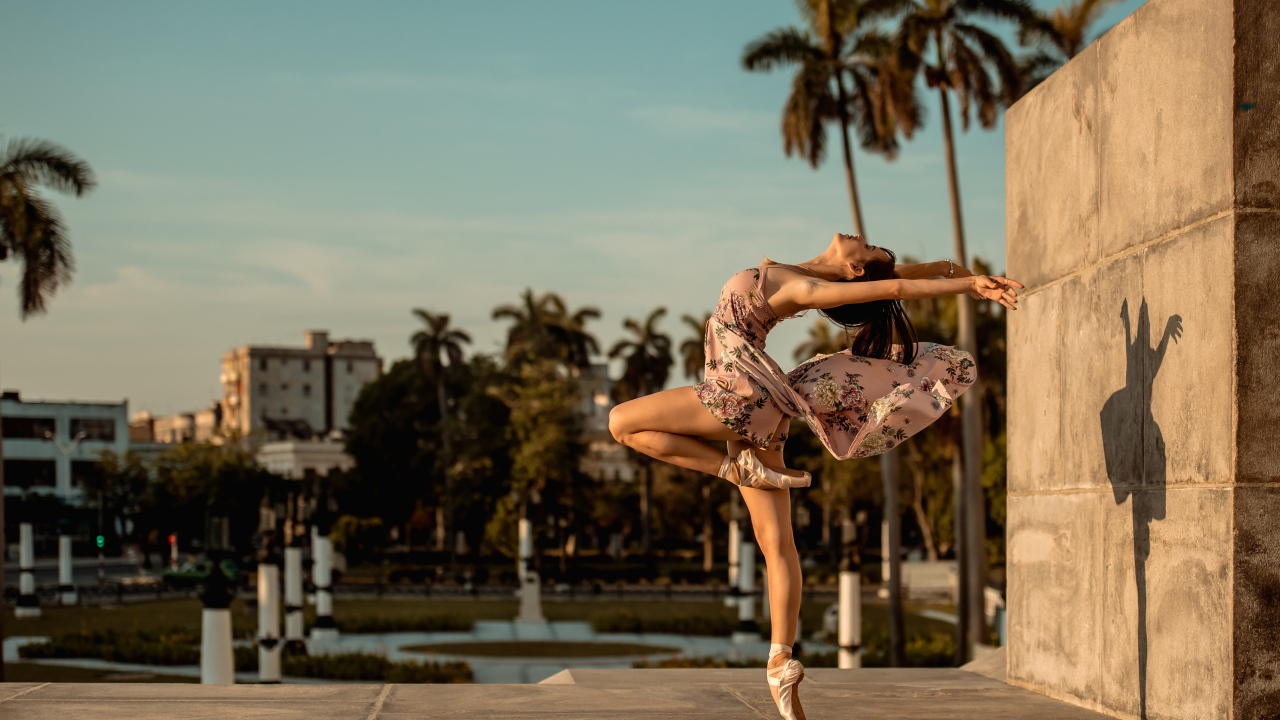 Девушка балерина в платье в красивой позе в лучах солнца