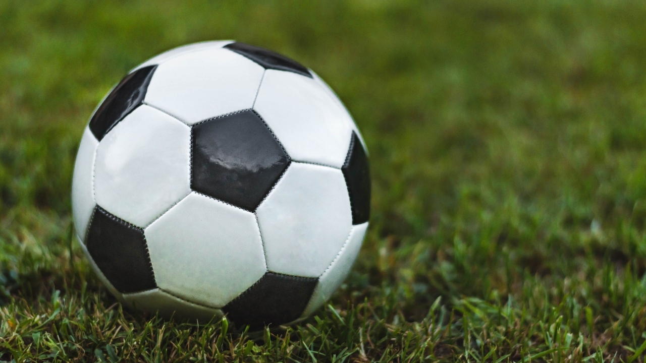 Футбольный мяч лежит на зеленой траве 