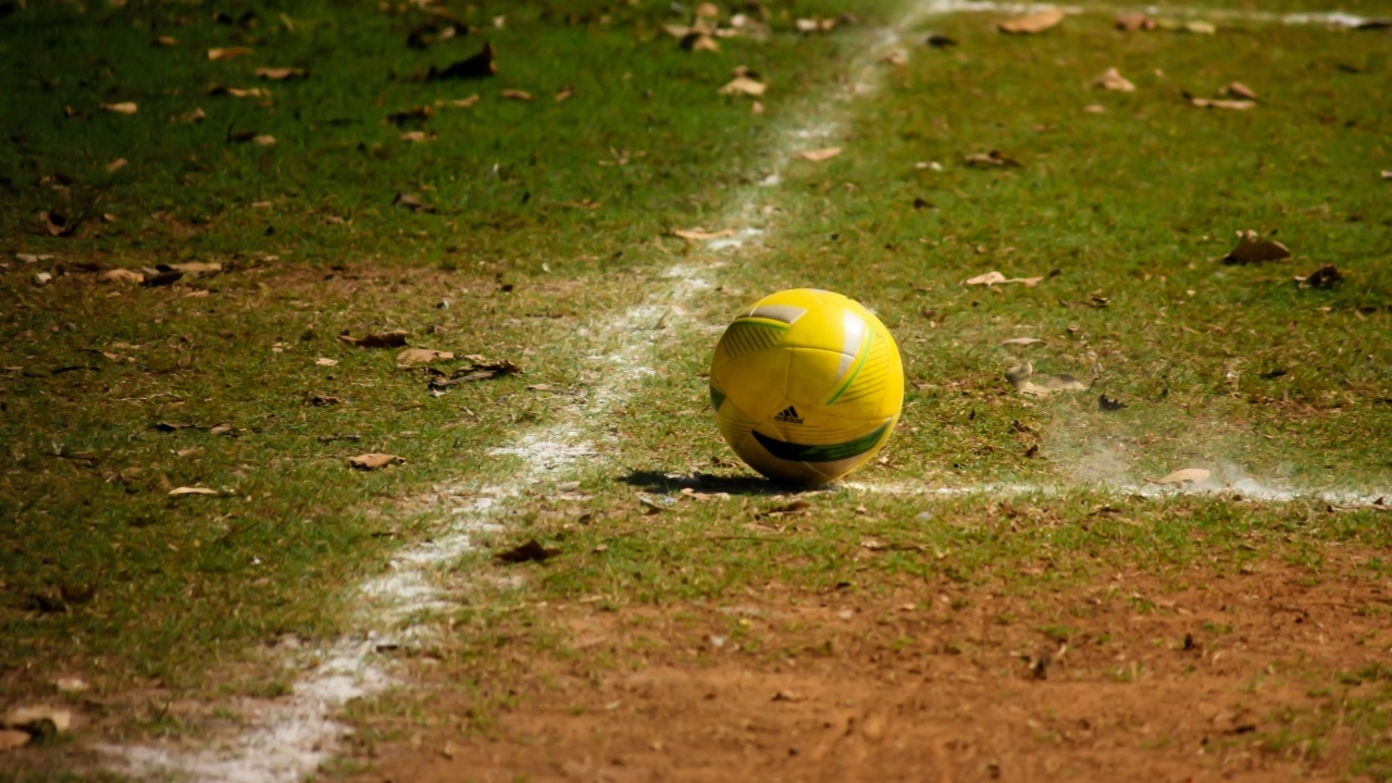 Желтый мяч на футбольном поле осенью 