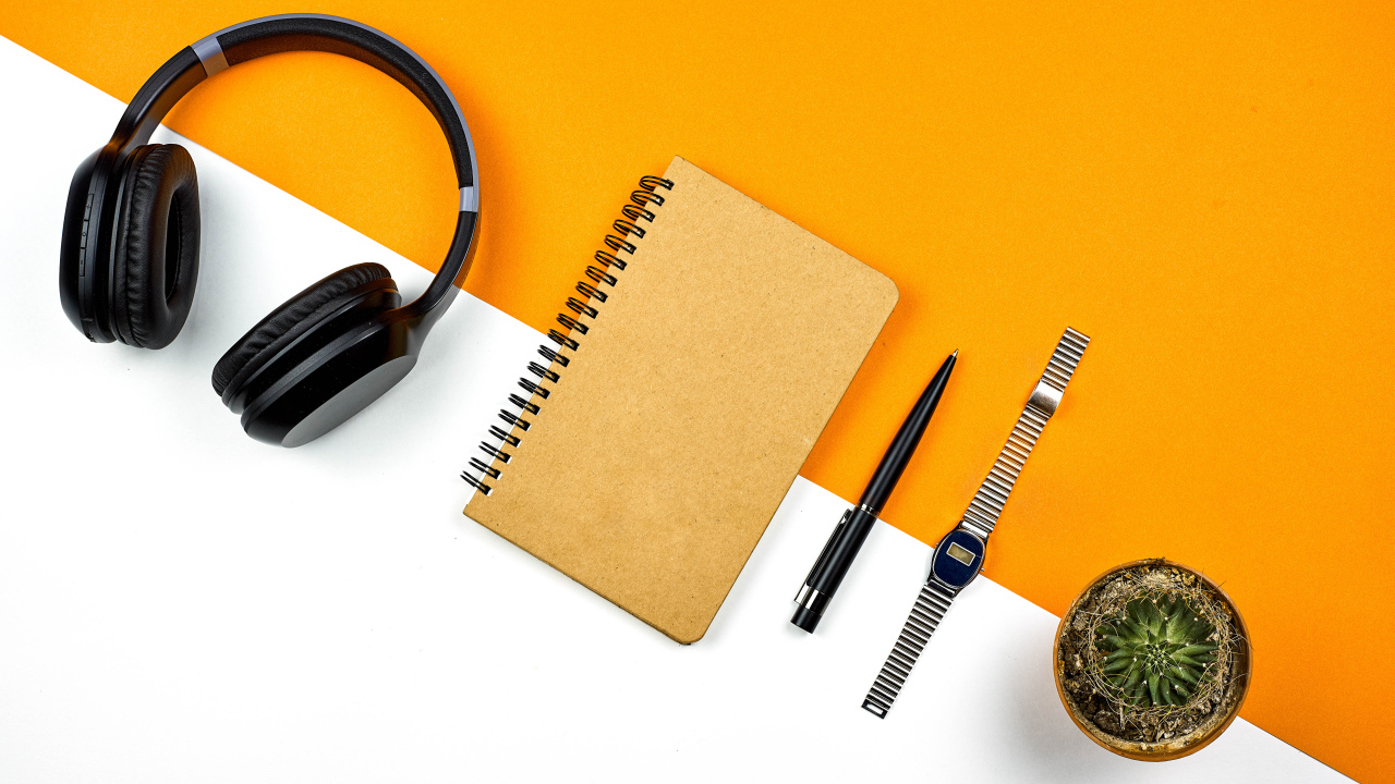 Наушники, блокнот, ручка, часы и цветок на фоне