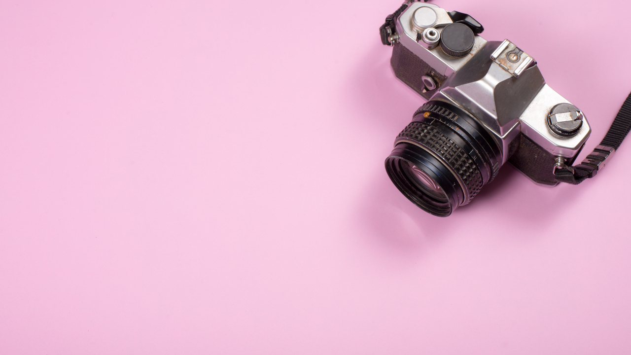 Старый фотоаппарат на розовом фоне