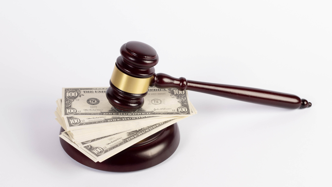 Молоток судьи и пачка долларов на белом фоне