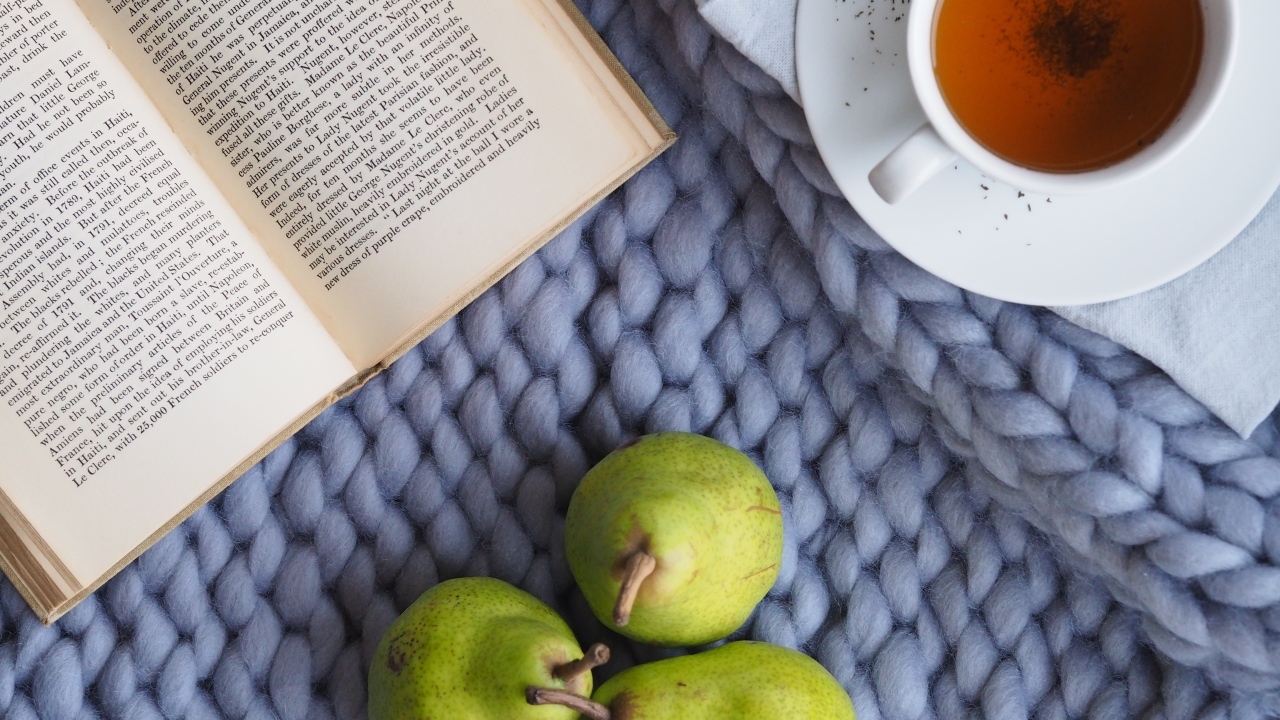 Три зеленые груши на столе с чаем и книгой