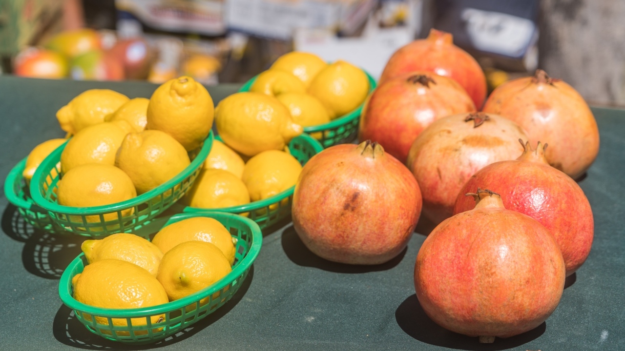 Желтые лимоны и красные плоды граната на столе