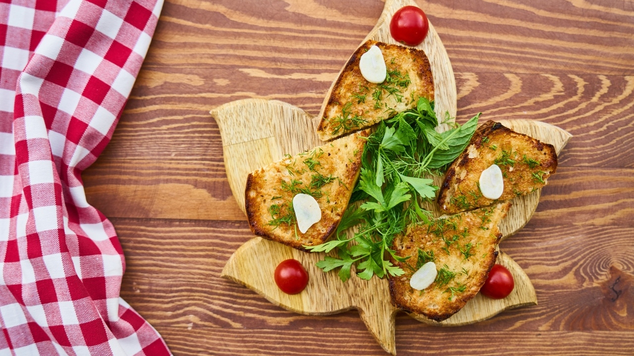 Гренки с чесноком и зеленью на разделочной доске на столе