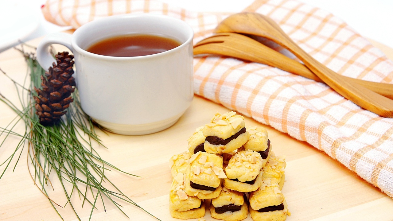Печенье с чашкой чая и сосновой шишкой на столе