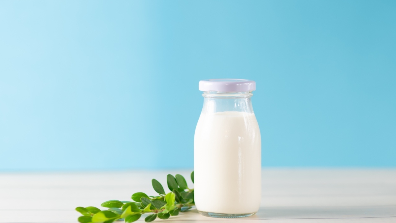 Бутылка молока с листьями на голубом фоне