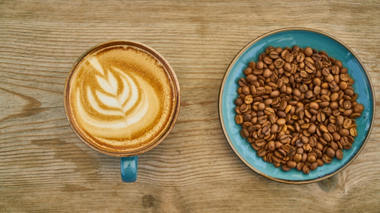 Чашка кофе с рисунком на столе с зернами