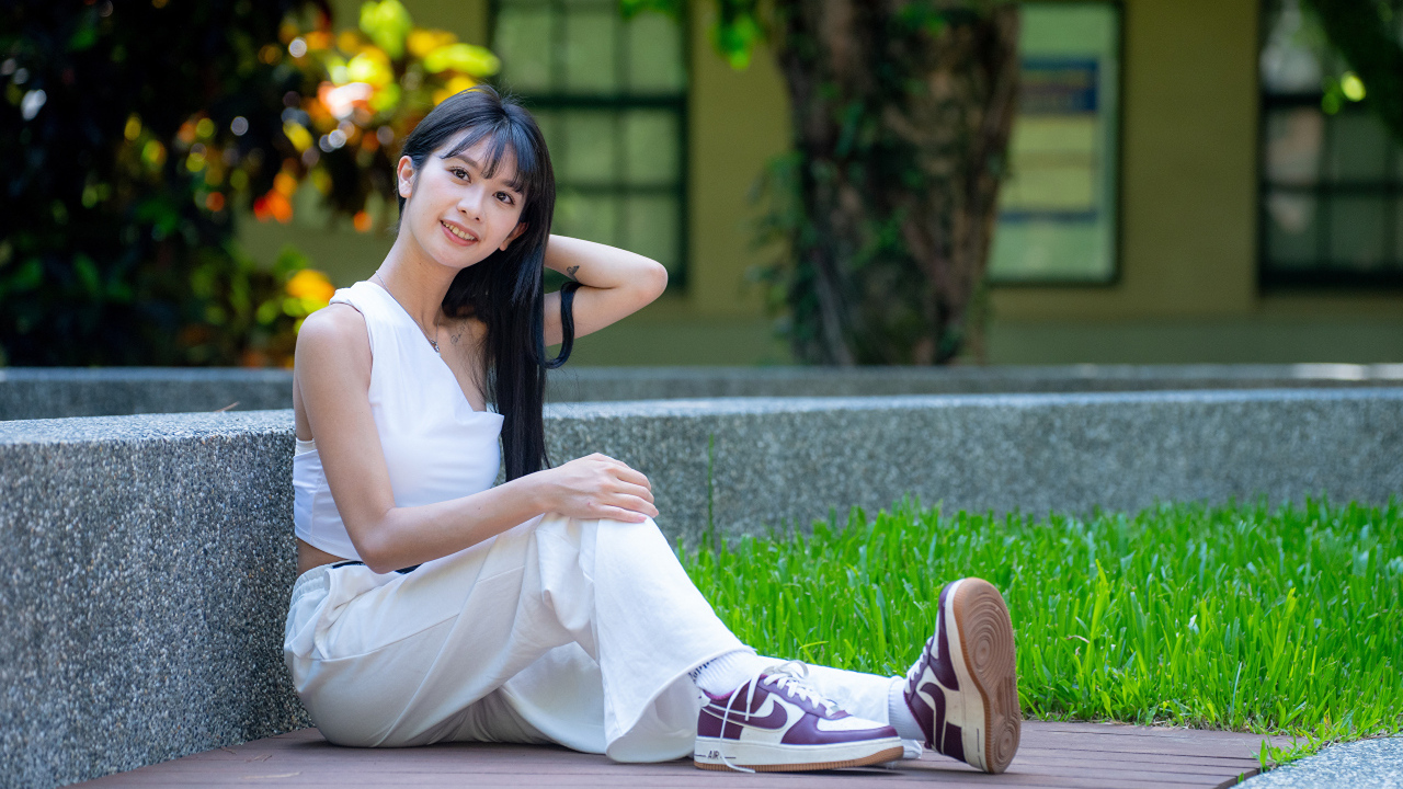 Девушка азиатка в белой костюме сидит на земле