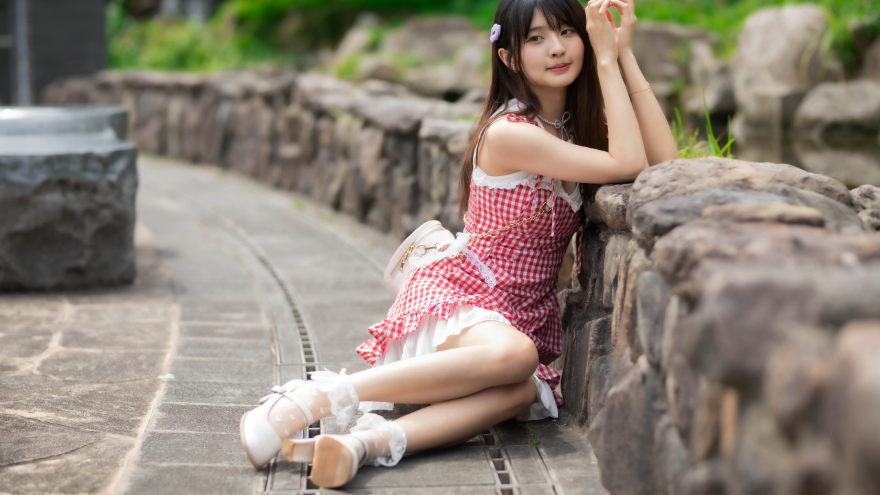 Азиатка сидит на земле в красном платье