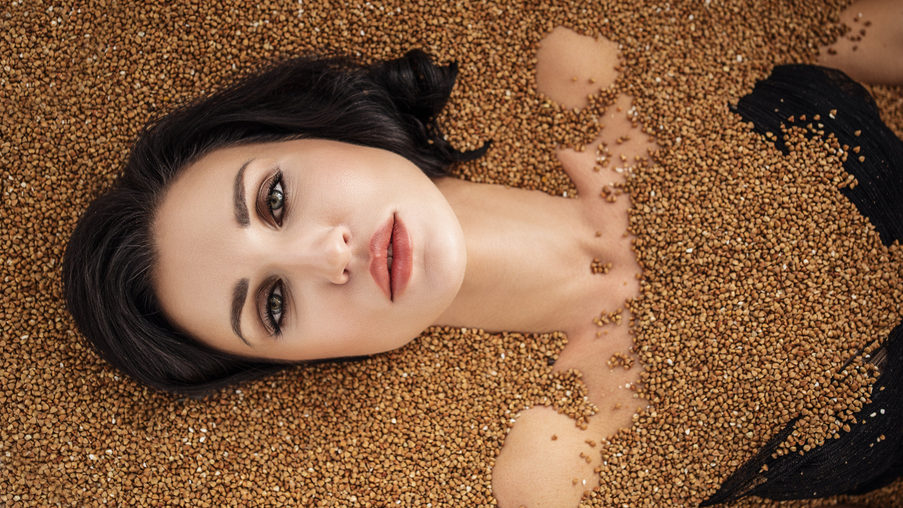Красивая девушка лежит в зернах гречки