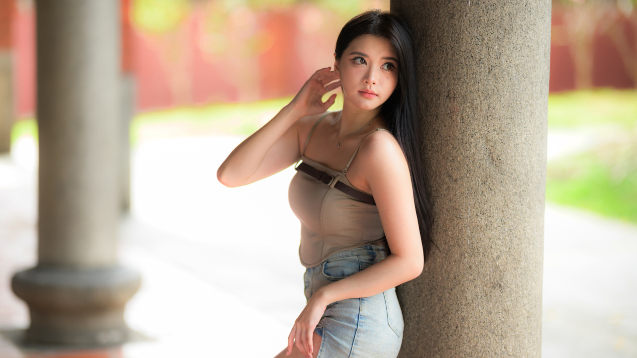 Милая длинноволосая азиатка стоит у колонны