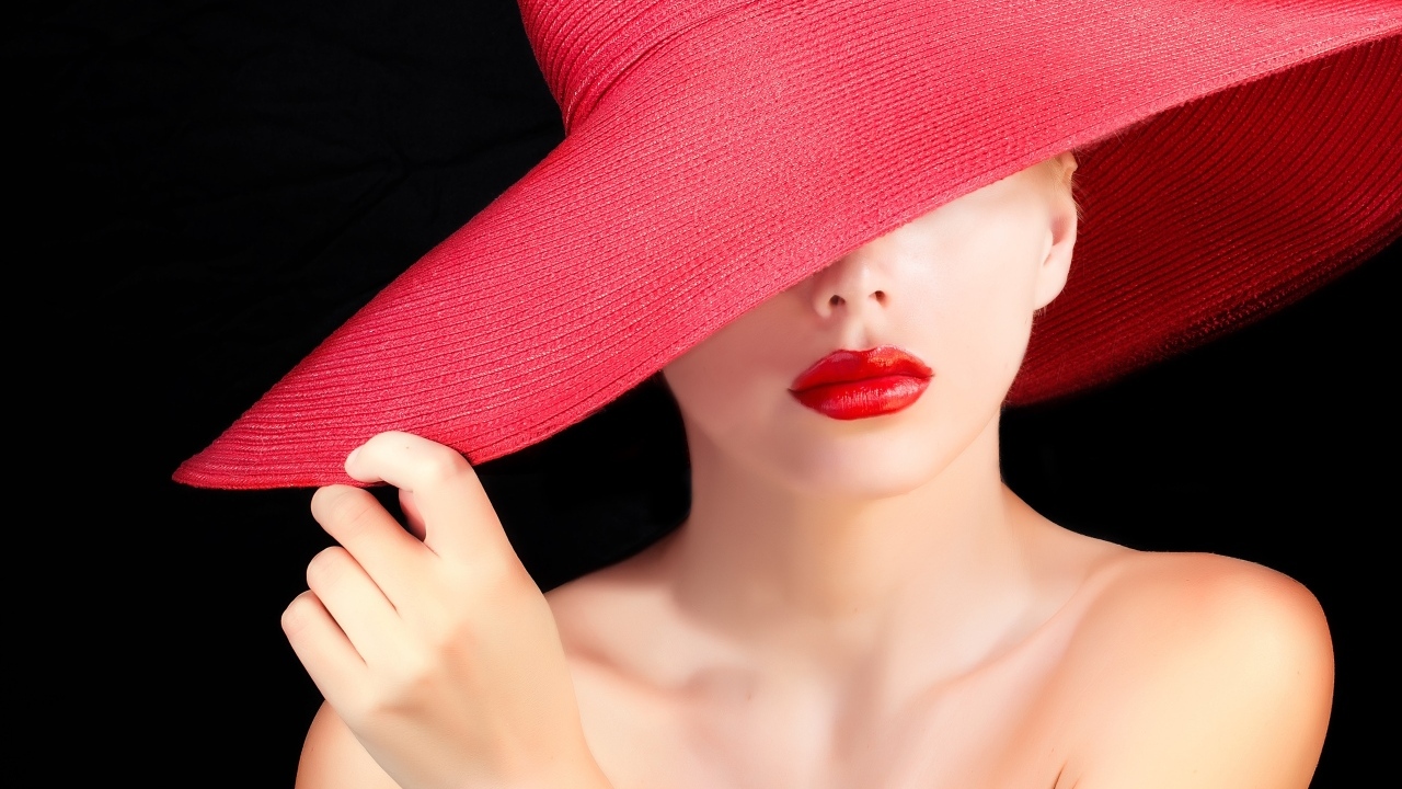 Девушка в большой красной шляпе на черном фоне