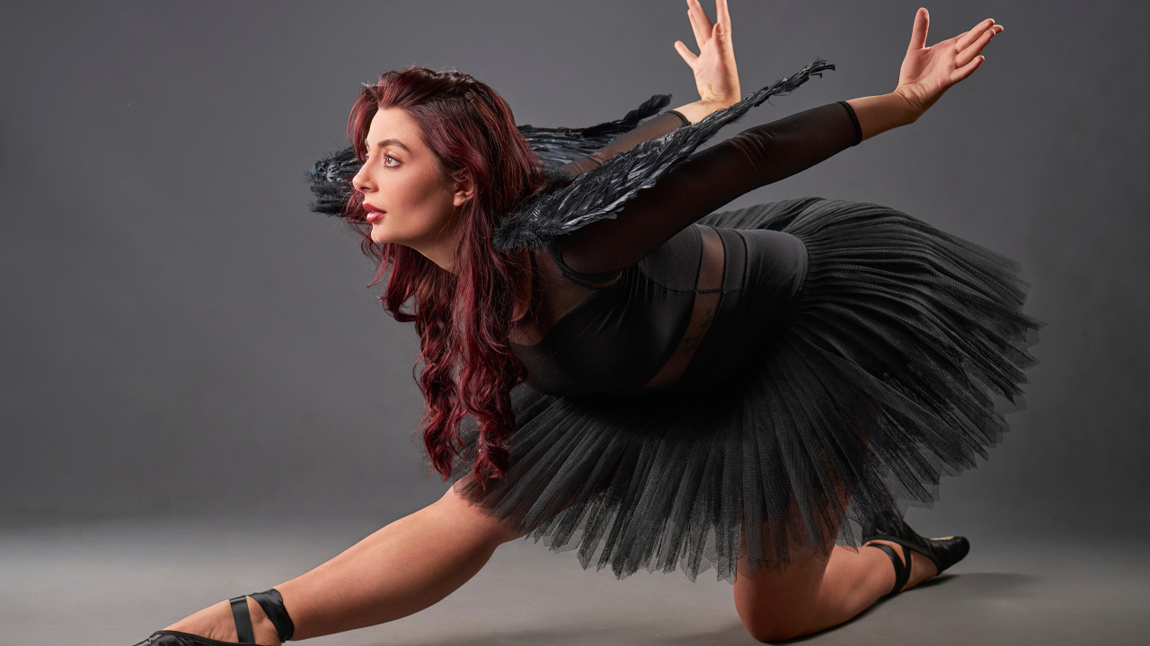 Девушка в черном костюме с крыльями танцует