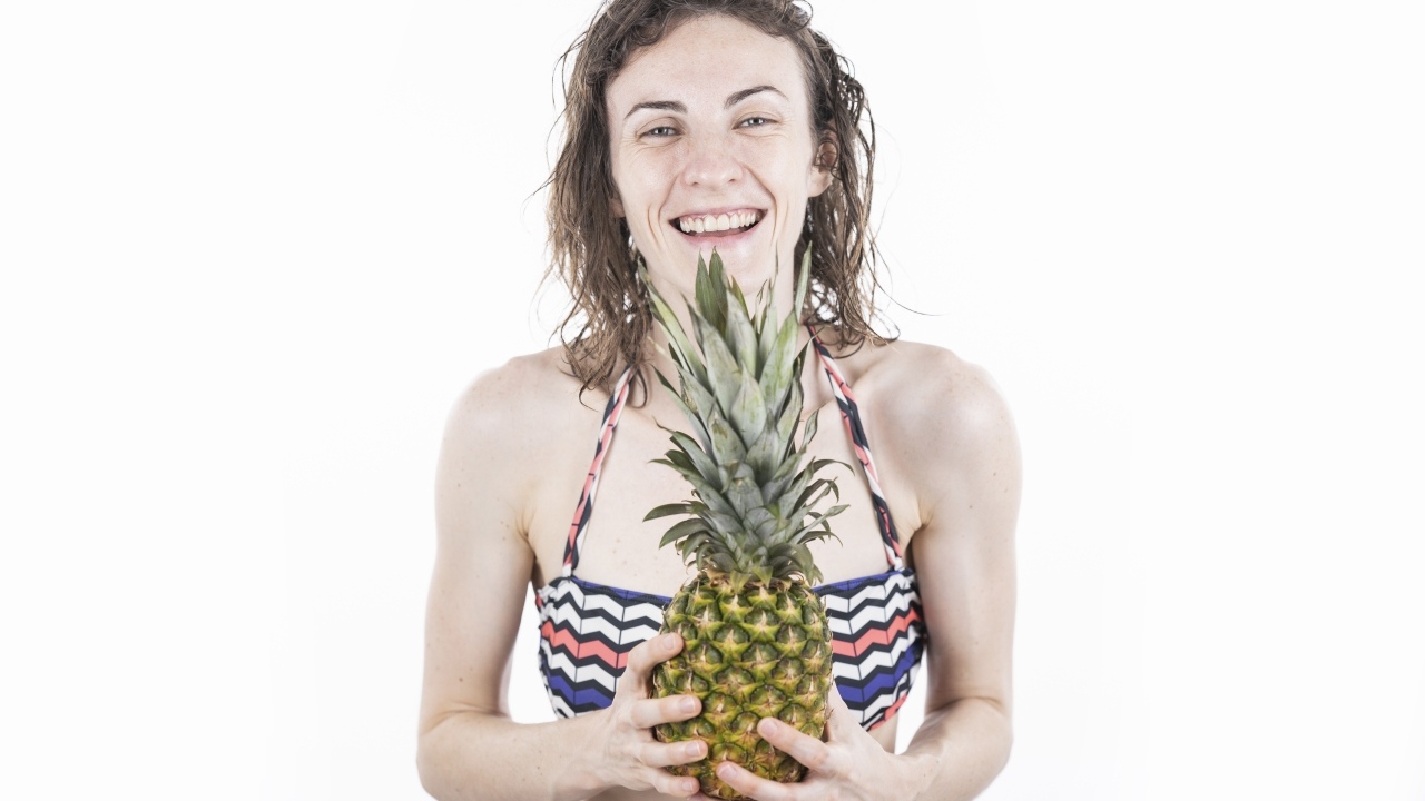 Улыбающаяся девушка с ананасом в руках