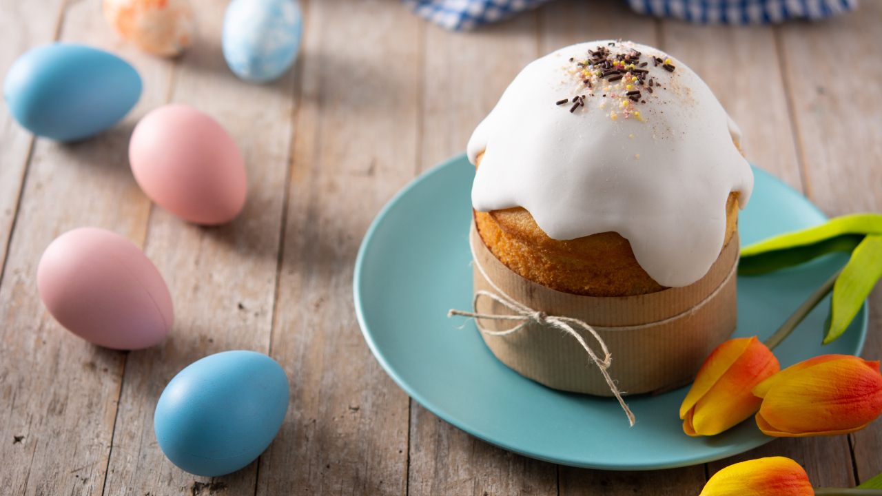 Кулич с крашеными яйцами и цветами на столе на Пасху