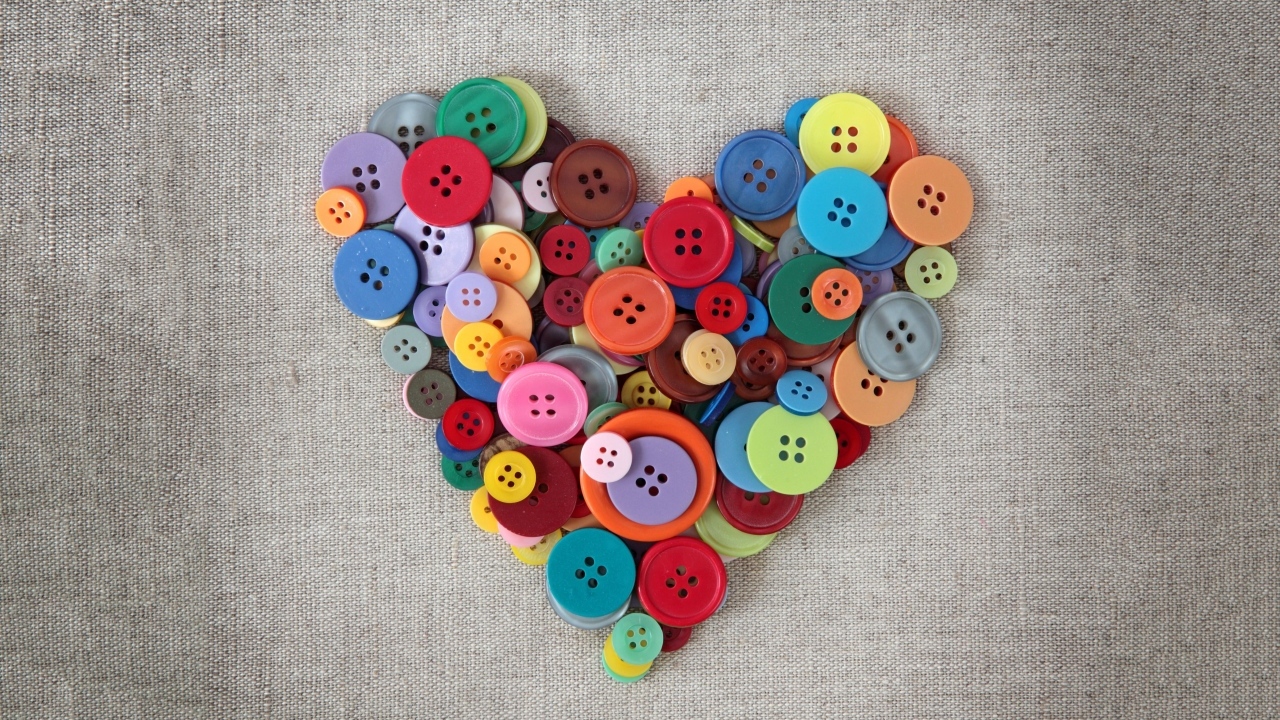 Сердце из разноцветных пуговиц на ткани 