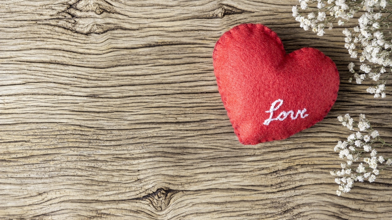 Красное тканевое сердце с цветами на деревянном столе