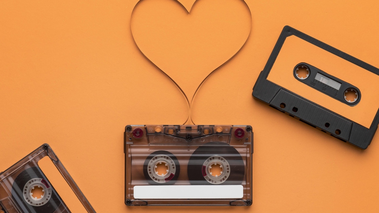 Кассеты и сердце из ленты на оранжевом фоне