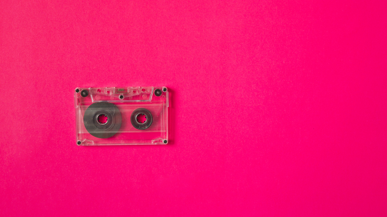 Маленькая магнитофонная кассета на розовом фоне