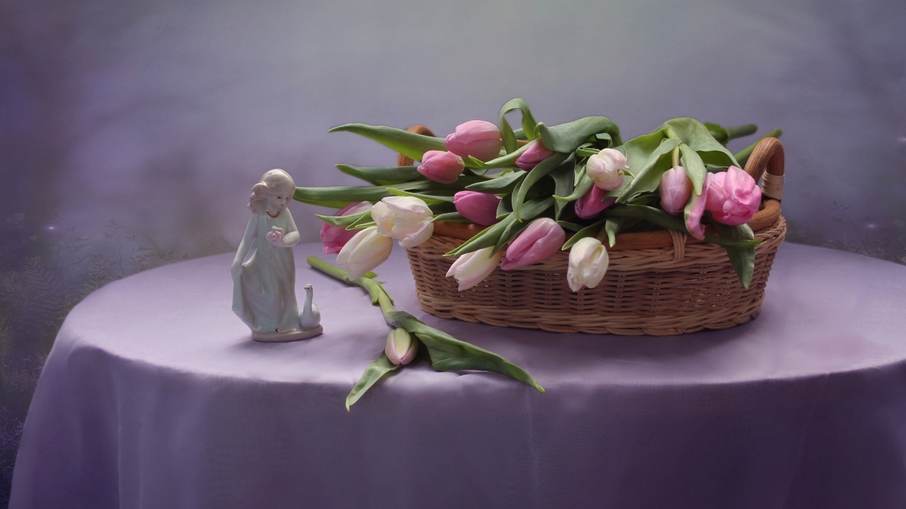 Корзина тюльпанов на столе со статуэткой