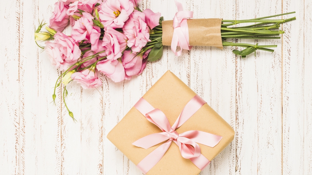 Букет розовых цветов эустомы с подарком на деревянном фоне