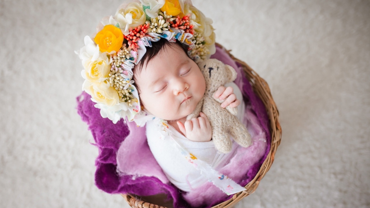 Младенец с венком на голове спит в корзине