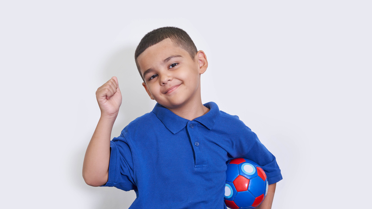 Милый мальчик с мячом на белом фоне