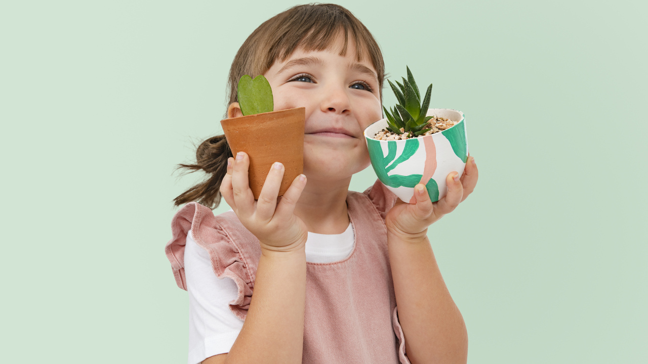 Маленькая девочка с комнатными цветами в руках