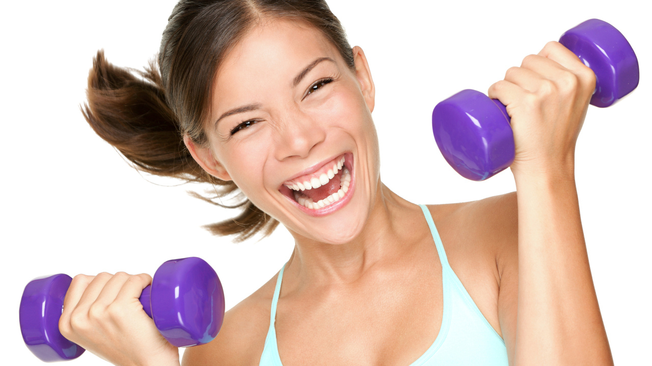 Веселая спортивная девушка с гантелями в руках