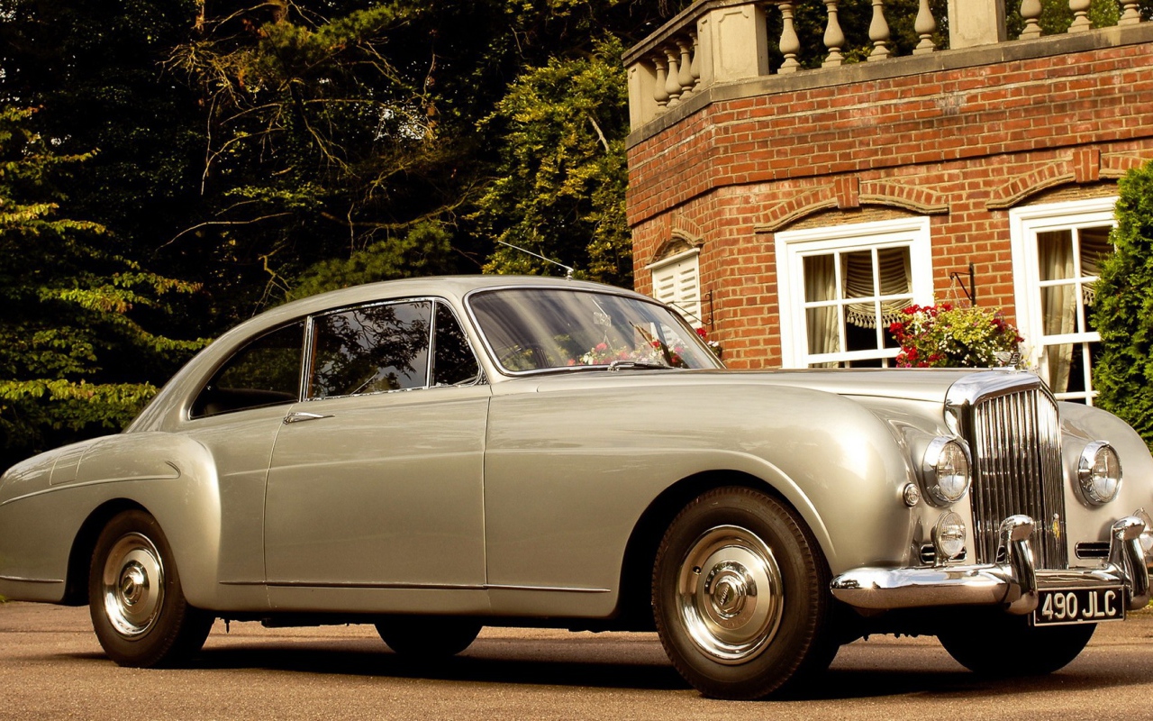 Белый автомобиль у кирпичного дома