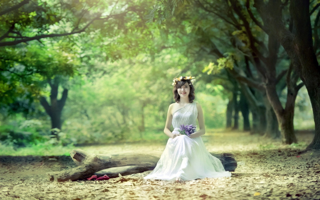 Девушка сидит на бревне